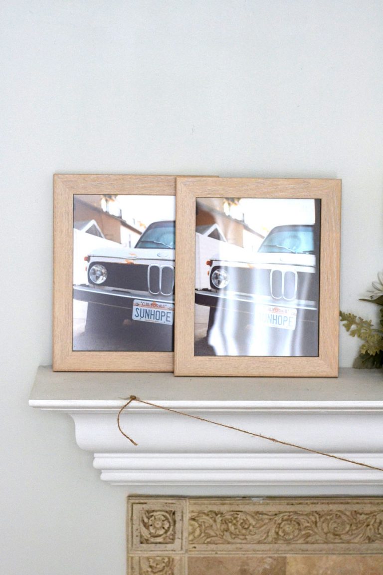 Two framed pictures of BMW cars on a white wall above a fireplace.